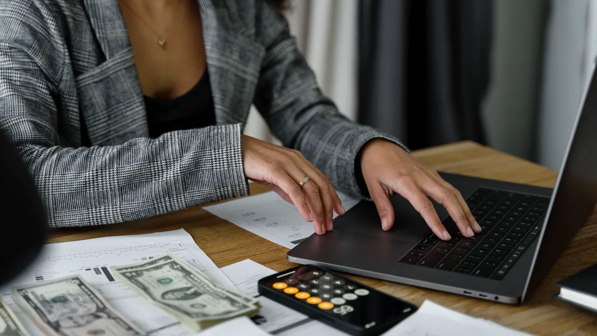 Businesswoman calculating costs with cash and a calculator